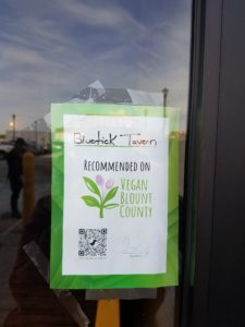 Sign on restaurant door that says BlueTick Tavern recommended by Vegan Blount County